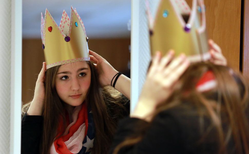Ein Mädchen betrachtet sich im Spiegel und setzt sich eine Sternsingerkrone.